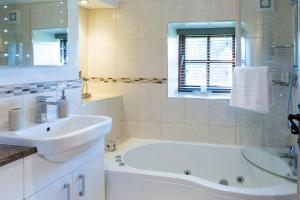 een witte badkamer met een bad en een wastafel bij Old Coach House Snowdonia in Betws-y-coed