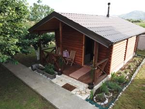 a small wooden cabin with a porch and a chair at Eko Apartmani Krackovic in Podgorica
