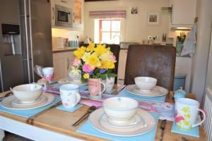a table with plates and cups and a vase of flowers at Old Coach House Snowdonia in Betws-y-coed