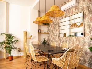 jadalnia z czarnym stołem i rattanowymi krzesłami w obiekcie Stylish Apartment in the heart of Málaga with Pool w Maladze