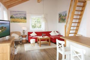 a living room with a red couch and a staircase at Haus Chiemsee-Blick in Gstadt am Chiemsee