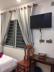 1 dormitorio con TV, mesa y silla en TWIN HOME Guesthouse, en Kampot