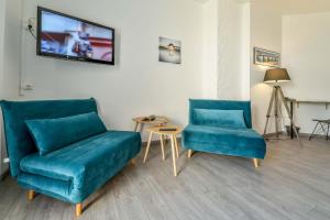 a living room with two blue chairs and a tv at Logis Hostellerie du Neez in Gan