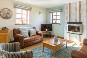 a living room with a leather couch and a fireplace at Tryfan Cottage in Betws-y-coed