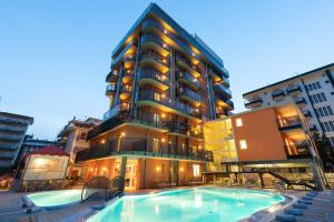 a hotel with a swimming pool in front of a building at Hotel Sheila in Lido di Jesolo