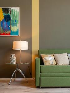 a green couch and a table with a lamp at Spluga Sosta & Hotel in Dubino
