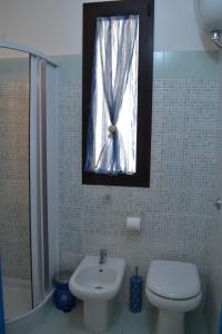 bagno con servizi igienici, lavandino e finestra di Casa Vacanze La Vela a Murta Maria