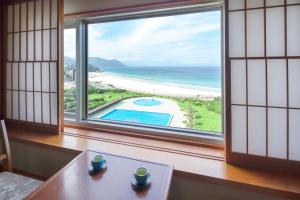 Hotel Izukyu في شيمودا: غرفة مع طاولة وإطلالة على المحيط