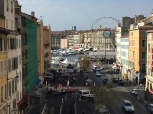 una concurrida calle de la ciudad con una noria en el fondo en Breteuil – Appart au Vieux Port en Marsella