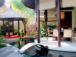 a house with a swimming pool and a house with a garden at Sandi Kala Villas in Kerobokan