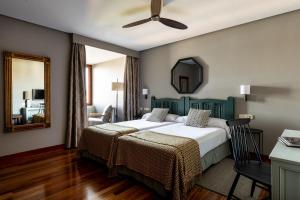 sypialnia z dwoma łóżkami i lustrem w obiekcie Parador de Hondarribia w mieście Hondarribia