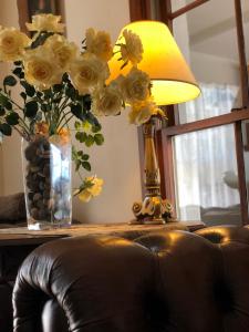 a table with a lamp and a vase of yellow roses at Gracehill Accommodation in Olinda