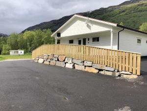 a house with a wooden fence next to a driveway at Saltvold leilighet nr1 in Røldal