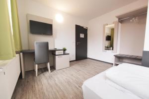a bedroom with a bed and a desk and a chair at bestprice Hotel Eschweiler in Eschweiler
