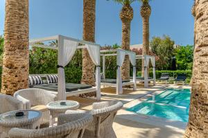 a patio area with tables, chairs and umbrellas at Drossia Palms Hotel and Nisos Beach Suites in Malia