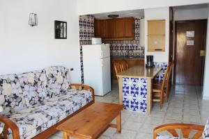 Una sala de estar con un sofá y una mesa y una cocina. en Apartamentos Las Americas - Blanes Beach, en Blanes