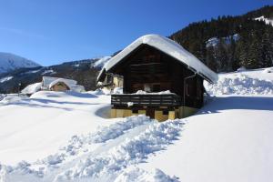 Cabaña cubierta de nieve con una pila de nieve en Blockhütte Radmer, en Radmer an der Hasel