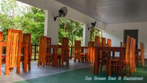 a group of wooden chairs and tables in a room at Sun Breeze Rest & Restaurant in Dambulla