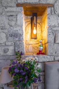 a light on a brick wall with flowers and a lamp at Çona Butik Otel in Alacati