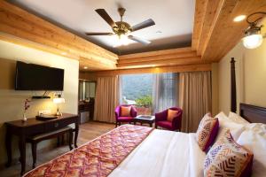 a hotel room with a bed and a desk and a television at Regenta Inn by Riverside Manali in Manāli