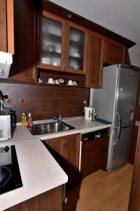 a kitchen with wooden cabinets and a stainless steel refrigerator at апартамент за гости Георгиеви in Veliko Tŭrnovo