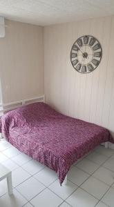 ナルボンヌ・プラージュにあるLes Cigalesの紫色のベッド1台、壁に時計が備わるベッドルーム1室が備わります。
