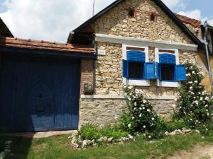una antigua casa de piedra con persianas azules y garaje en Casa Anca Cheile Nerei, en Socolari