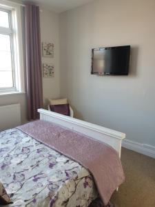 a bedroom with a bed and a flat screen tv on the wall at The Beach Hut in Bridlington