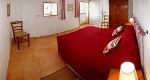 a bedroom with a red bed with a red blanket at Gîte Domaine Le Fragnaud in Saint-Porchaire