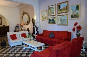 a living room with a red couch and two white chairs at Hotel Santa Amalia in Vassouras
