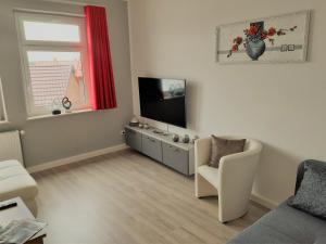 a living room with a flat screen tv and a chair at Hotel Fabrice in Bad Klosterlausnitz