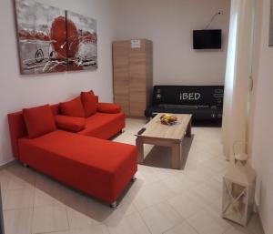 a living room with a red couch and a coffee table at Elena Rooms-Apartments in Asprovalta