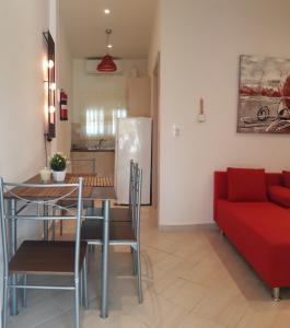 a living room with a table and a red couch at Elena Rooms-Apartments in Asprovalta