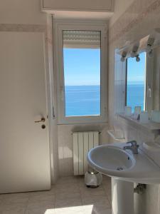 a white bathroom with a sink and a window at Albergo Miramare in Bergeggi