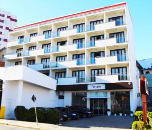 a large white building with cars parked in front of it at Hotel Urupes in São Bento do Sul