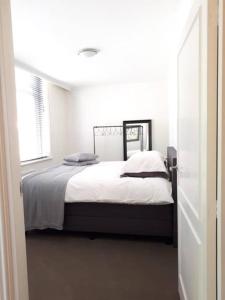 um quarto com uma cama com lençóis brancos e uma janela em In the old City Centre of Edam, unique apartment. em Edam