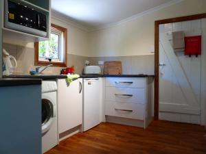 a kitchen with white cabinets and a washer and dryer at Andy's Accommodation in Peterborough +9 photos