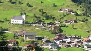 a village on a green hill with a church at Ferienwohnung Viehhauser in Hüttschlag