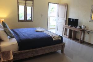 a bedroom with a bed and a tv and a door at Adore guesthouse in Amed