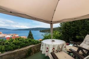 a table with an umbrella on a balcony with a view at Apartments and rooms Roberto B. in Valun
