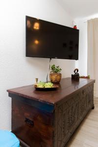 a television on top of a wooden table with a plate of food on it at Apartment Skroza 2 in Žirje