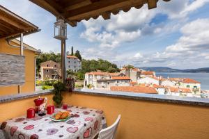 a table on a balcony with a view of the water at Apartments and rooms Roberto B. in Valun