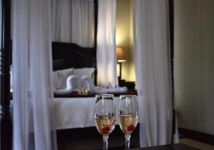 two wine glasses sitting on a table in a bedroom at Waterfalls Boutique Hotel in Pretoria