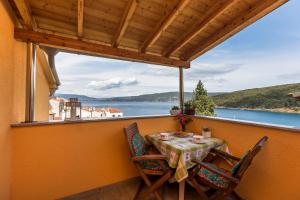 a table and chairs on a balcony with a view of the water at Apartments and rooms Roberto B. in Valun