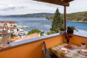 a table on a balcony with a view of the water at Apartments and rooms Roberto B. in Valun