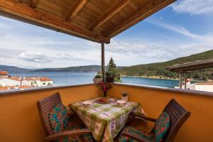 a table and chairs on a balcony with a view of the water at Apartments and rooms Roberto B. in Valun