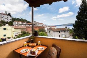 a table on a balcony with a view of a city at Apartments and rooms Roberto B. in Valun