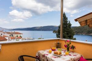 a table with food and flowers on a balcony with a view at Apartments and rooms Roberto B. in Valun