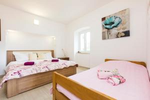 two beds in a bedroom with white walls at Apartments and rooms Roberto B. in Valun +89 photos
