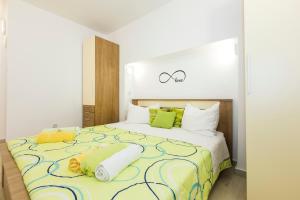 a bedroom with a large bed with green and yellow sheets at Apartments and rooms Roberto B. in Valun